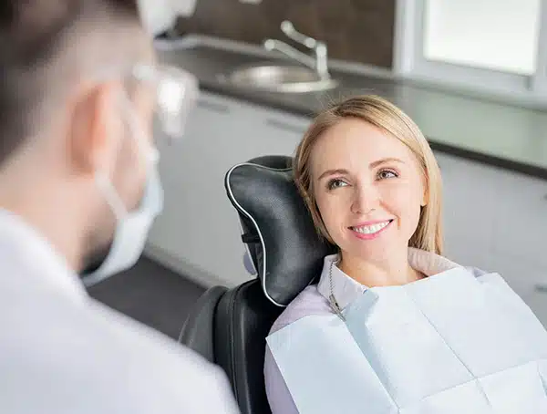Woman smiling in dental chair during consultation with dentist in modern clinic.