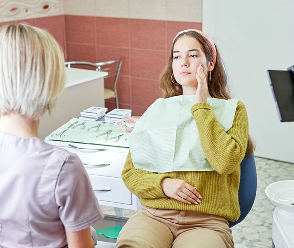 Healthcare provider consulting with patient in dental office examination room.