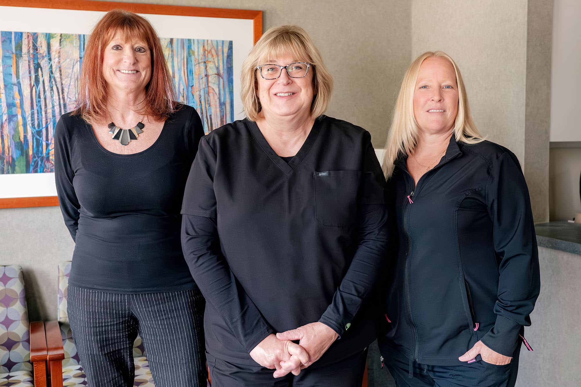Three women staff members standing together in a dental office at Brighton Healthy Smiles.