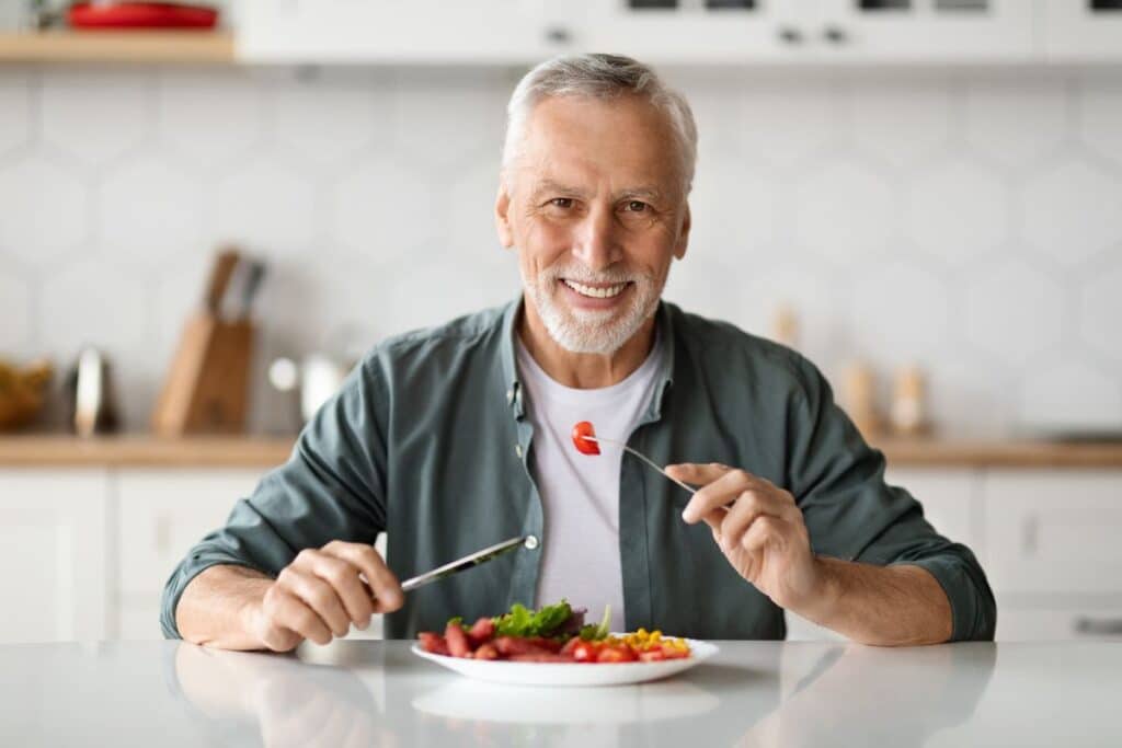 Senior man enjoying a healthy meal, demonstrating improved chewing ability and comfort after restoring missing teeth.