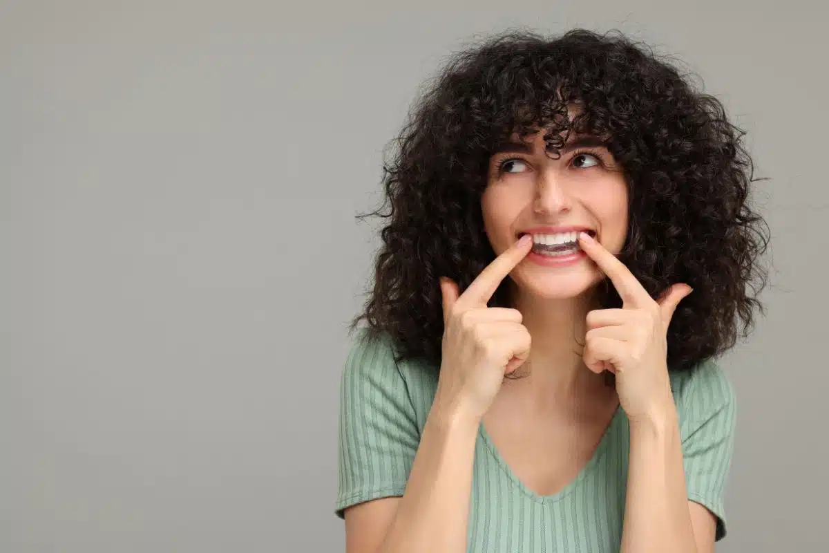 A woman showing her teeth while checking their appearance, representing professional teeth whitening, whitening maintenance, and ways to keep teeth looking brighter for longer.